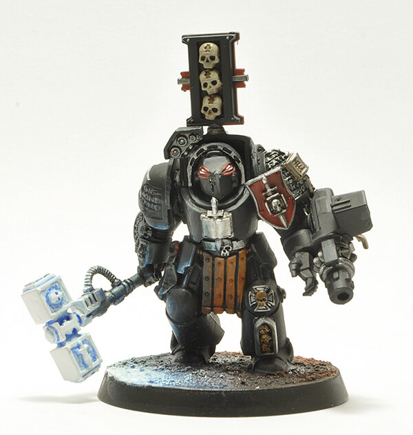 Ordo Malleus in dark armor with red shield and accenting. Giant silver hammer in hand.