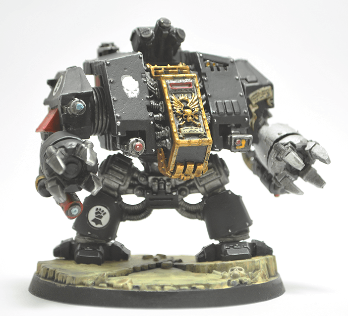 A Deathwatch Dreadnought model in black armor with a claw arm and intricate gold details.