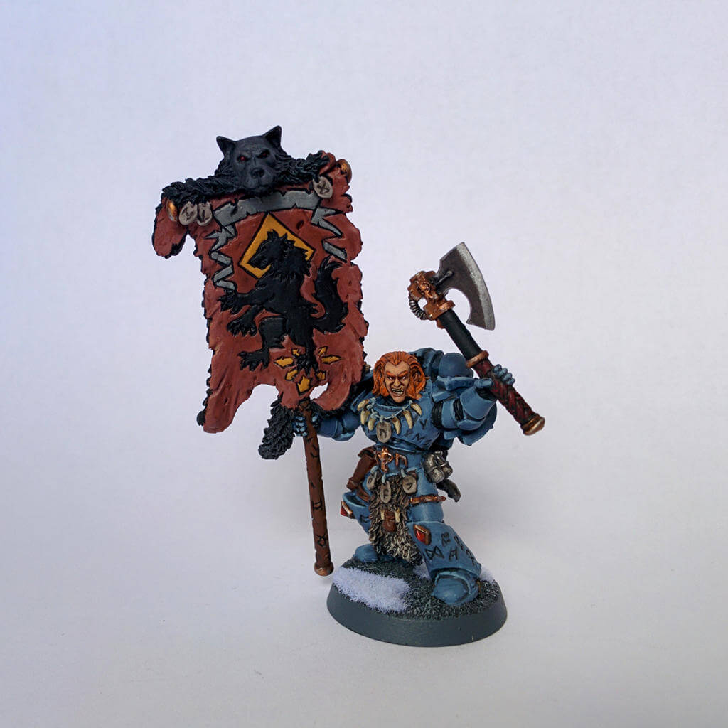 Space Wolves model carrying a wolf-pelt banner and axe, painted in icy blue-gray armor.